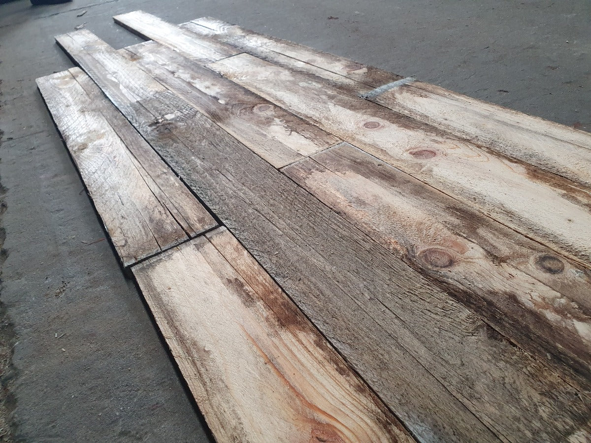 Stapel hergebruikte naaldhouten planken, achtergelaten door een oude fabriek, getransformeerd tot prachtige vintage houten elementen door het duurzame team van Recupwood.